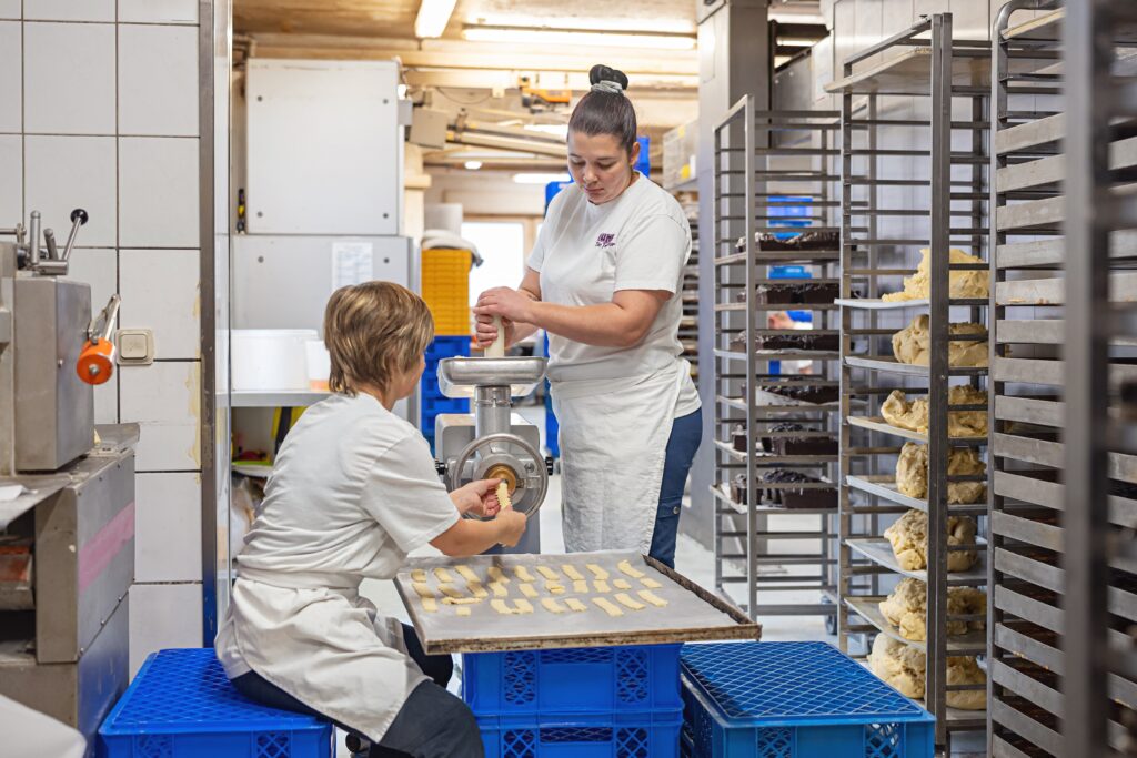 Mehrere Bäcker arbeiten gemeinsam an der Teigzubereitung in der Backstube.